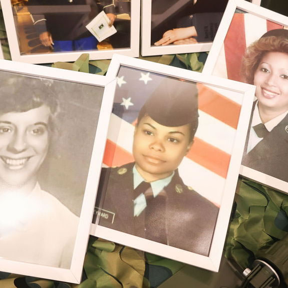 Framed portraits of women veterans displayed on a camouflage-patterned table