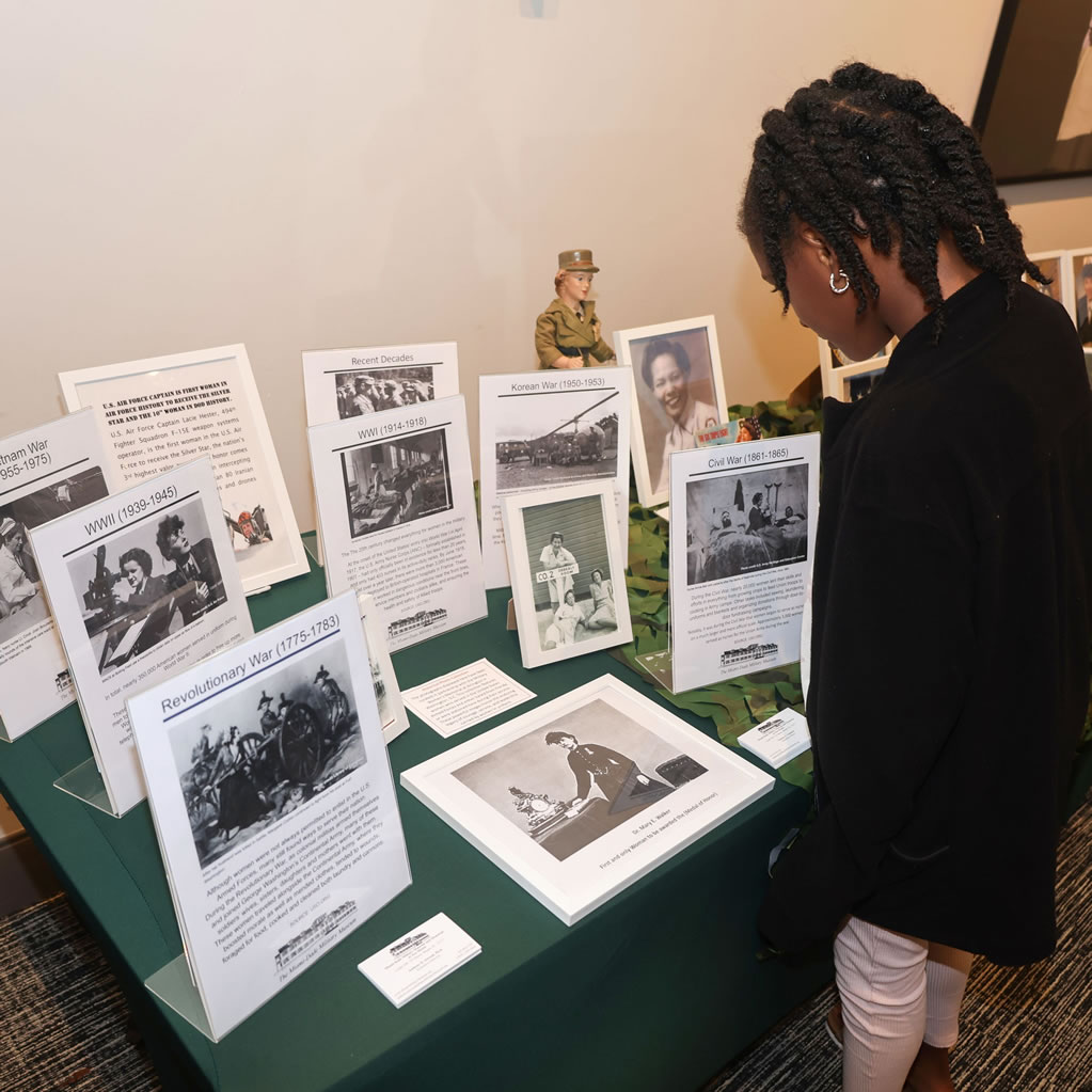 Woman reading a timeline display of women's military service from the Revolutionary War to today