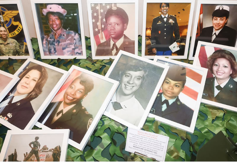 Framed portrait photos of women veterans in uniform displayed on a camouflage table